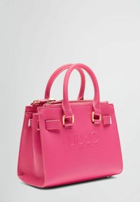 Sac à main structuré rose avec deux poignées en haut et quincaillerie dorée. Présente un logo en relief et un matériau synthétique texturé. Fermeture à glissière.