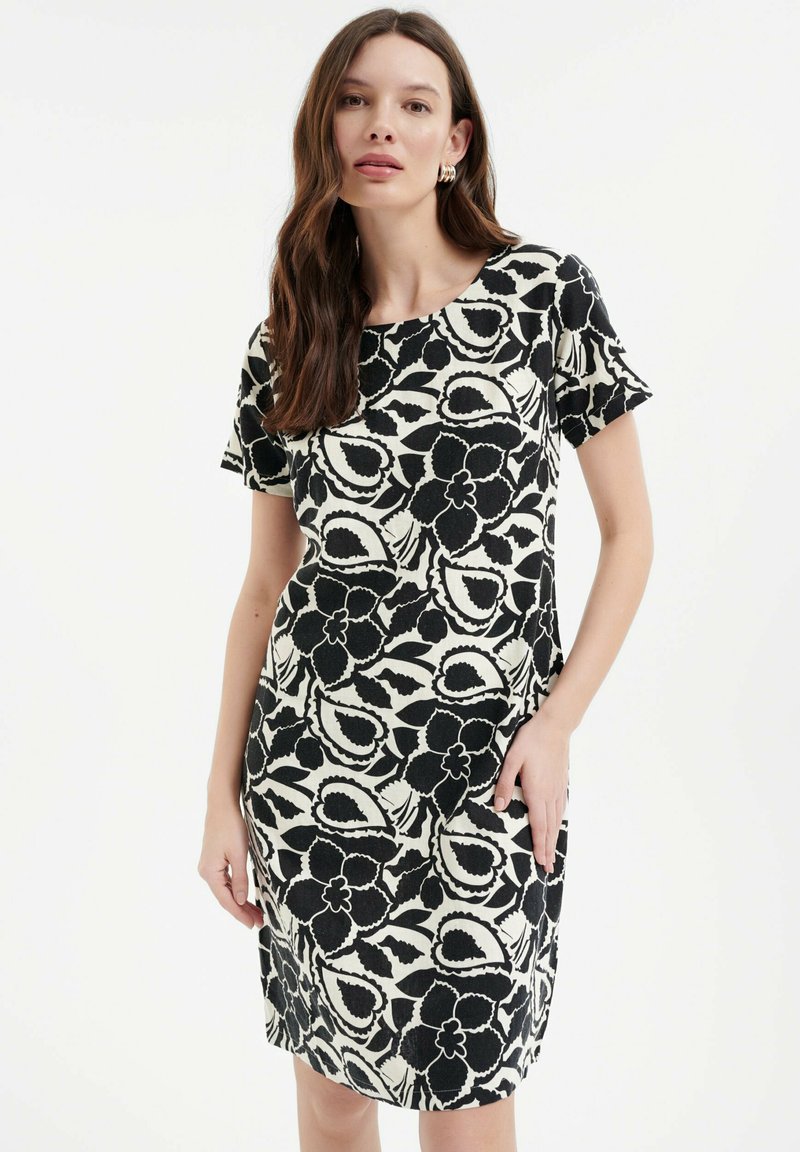 Czarna i biała sukienka w kwiatowy wzór z krótkimi rękawami, okrągłym dekoltem i bocznymi kieszeniami; lekko dopasowana, do kolan.