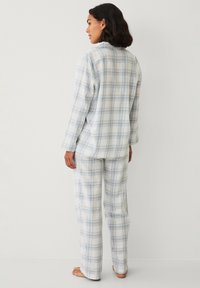 Geruite pyjama set van lichtgewicht stof, met blauwe en grijze ruitpatronen, lange mouwen en losse broek.