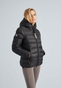 Svart pufferjacka med huva, med horisontella quiltade sektioner, frontdragkedja och logodetalj på bröstet. Mjuk, glänsande textur.