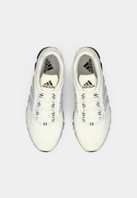 Pair of white Adidas running shoes with black logo on tongue and inner sole, viewed from above on white background.