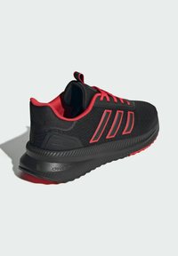 Czarny sportowy but z górną częścią z teksturowanej tkaniny i czerwonymi akcentami. Posiada trzy paski, amortyzowaną podeszwę i pętelkę do zakładania.