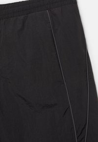 Schwarze Nylon-Sportshorts mit elastischem Bund und seitlichen Taschen, die mit reflektierendem Paspel abgesetzt sind.