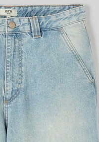 Jeans en denim bleu clair avec une taille haute, présentant un bouton de fermeture, des poches avant et des accents de décoloration subtils.