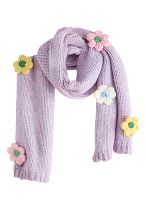 Donna che indossa un maglione grigio e jeans azzurri chiari con una sciarpa lavorata a maglia lavanda decorata con tre applicazioni floreali colorate.