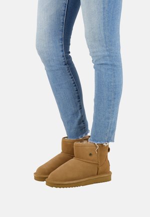 Bruine suède enkelbotten met een ronde neus en een zachte voering, gecombineerd met blauwe skinny jeans met rafelige zomen.