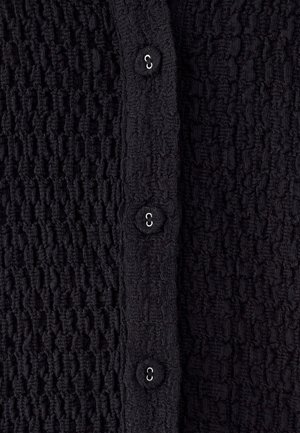 Must tekstuuriga kardigan, millel on kortsus muster, viis kangaga kaetud nööpi ees, sileda viimistluse ja peene läikega.