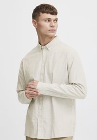 Stribet langærmet skjorte i blød beige og lys grønne nuancer, med button-down krave og manchetter, samt en afslappet pasform.