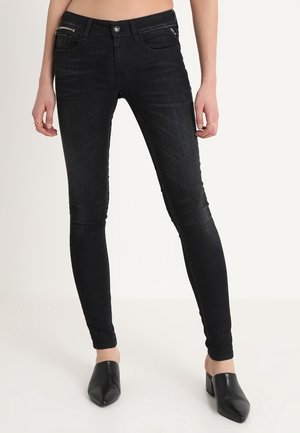 Jeans ajustados negros de denim con una textura suave, que cuentan con un bolsillo con cremallera, cierre frontal de botón y un diseño minimalista.