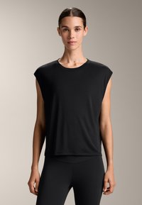 Top senza maniche nera con scollo rotondo. Realizzato in tessuto morbido, presenta una vestibilità relax e un design con spalla scesa.