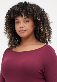 Burgundy long-sleeve top with a wide scoop neckline, made of soft material, featuring a smooth texture and minimal stitching accents.