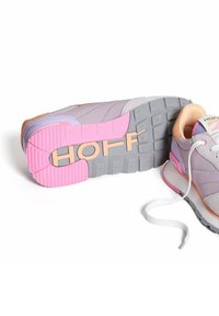 Zapatilla multicolor que presenta una parte superior de suave color lavanda, una entresuela de color rosa claro y una suela de goma texturizada en gris con la marca "HOFF".