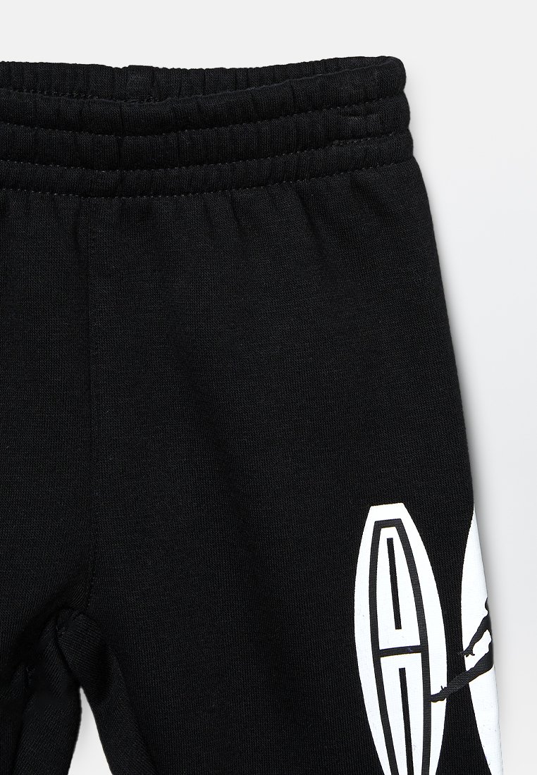 Pantalones deportivos negros con una cinturilla elástica, una textura suave y un logotipo blanco en la parte inferior de la pierna.
