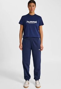 Marinblå bomulls-T-shirt med "hummel"-logotyp i vitt, kombinerad med matchande marinblå mjukisbyxor med resår i midjan och muddade benslut.