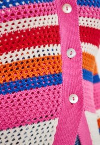 Färgglad stickad cardigan med rosa, röd, vit, blå och orange ränder, med en strukturerad öppen väv och runda metallknappar.