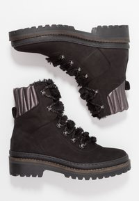 Botas negras con cordones, con un cuello de piel texturizada y detalles grises brillantes. Suela robusta con profundos surcos para mayor tracción. Material de ante.