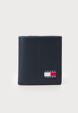 Navy leather wallet featuring a textured surface, folded design, and signature Tommy Jeans logo in red, white, and blue on the front.