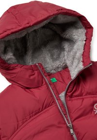Červená izolovaná bunda s kapucí lemovanou šedou kožešinou, zapínáním na zip a dekorativním prošíváním. Odolný vnější materiál pro teplo.