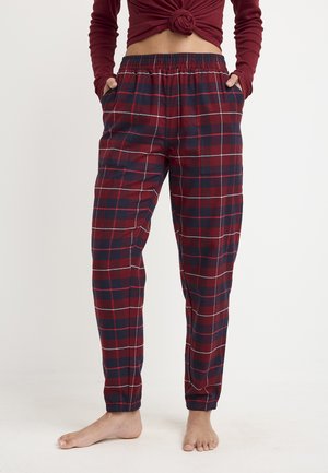 Red and navy plaid pajama pants made of soft fabric, featuring an elastic waistband, side pockets, and tapered cuffs at the ankles.