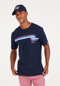Camiseta azul marino con cuello redondo, con rayas horizontales en rojo y azul claro. Mangas cortas, corte relajado, fabricada en algodón suave.