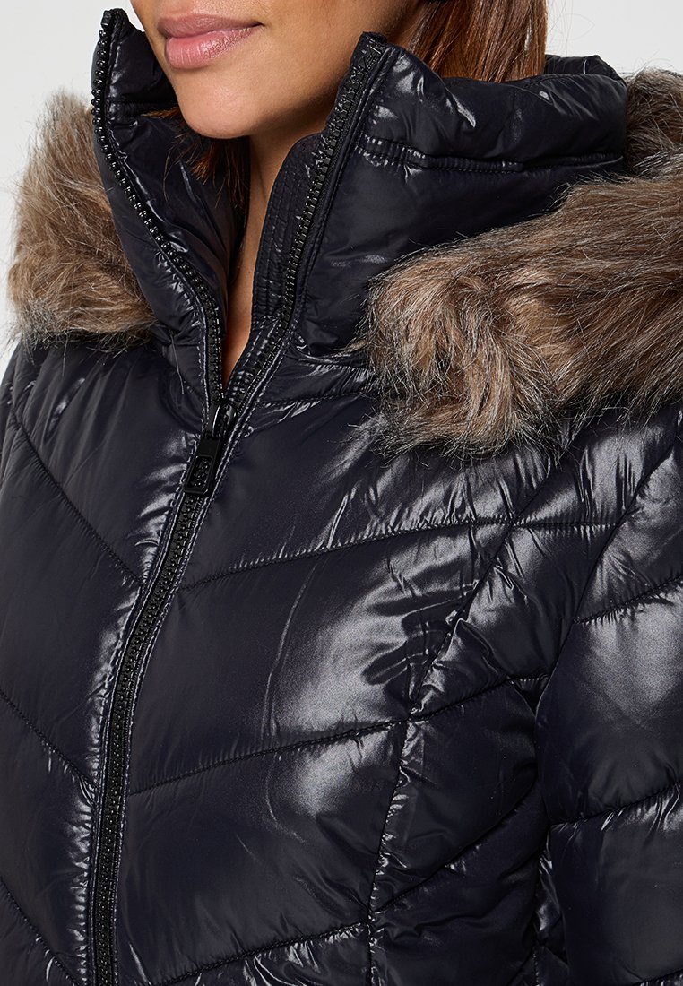 Dikke zwarte jas met een glanzende afwerking, voorzien van een met bont gevoerde capuchon en ritssluiting, horizontaal getailleerd ontwerp en opvallende stikseldetails.