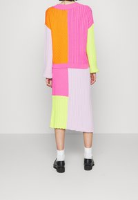 Sukienka dzianinowa z długimi rękawami; posiada patchwork w kolorach pomarańczowym, różowym, żółtym i lawendowym; teksturowana tkanina; prążkowane wykończenia na mankietach i u dołu.