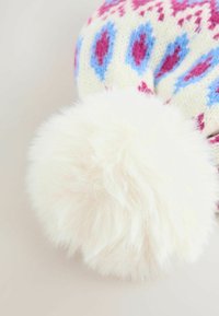 Bonnet en crème avec des motifs géométriques roses et bleus, présenté avec un grand pompon en fausse fourrure blanche et douce sur le dessus.