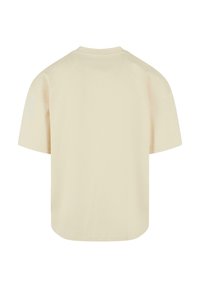 T-shirt à manches courtes en coton beige clair. Doté d'un col rond et d'une coupe décontractée et oversize avec un ourlet droit sans marque visible.