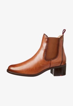Bottine en cuir marron avec panneaux élastiques sur les côtés, petit talon bloc, semelle texturée et petite boucle décorative à l'arrière.