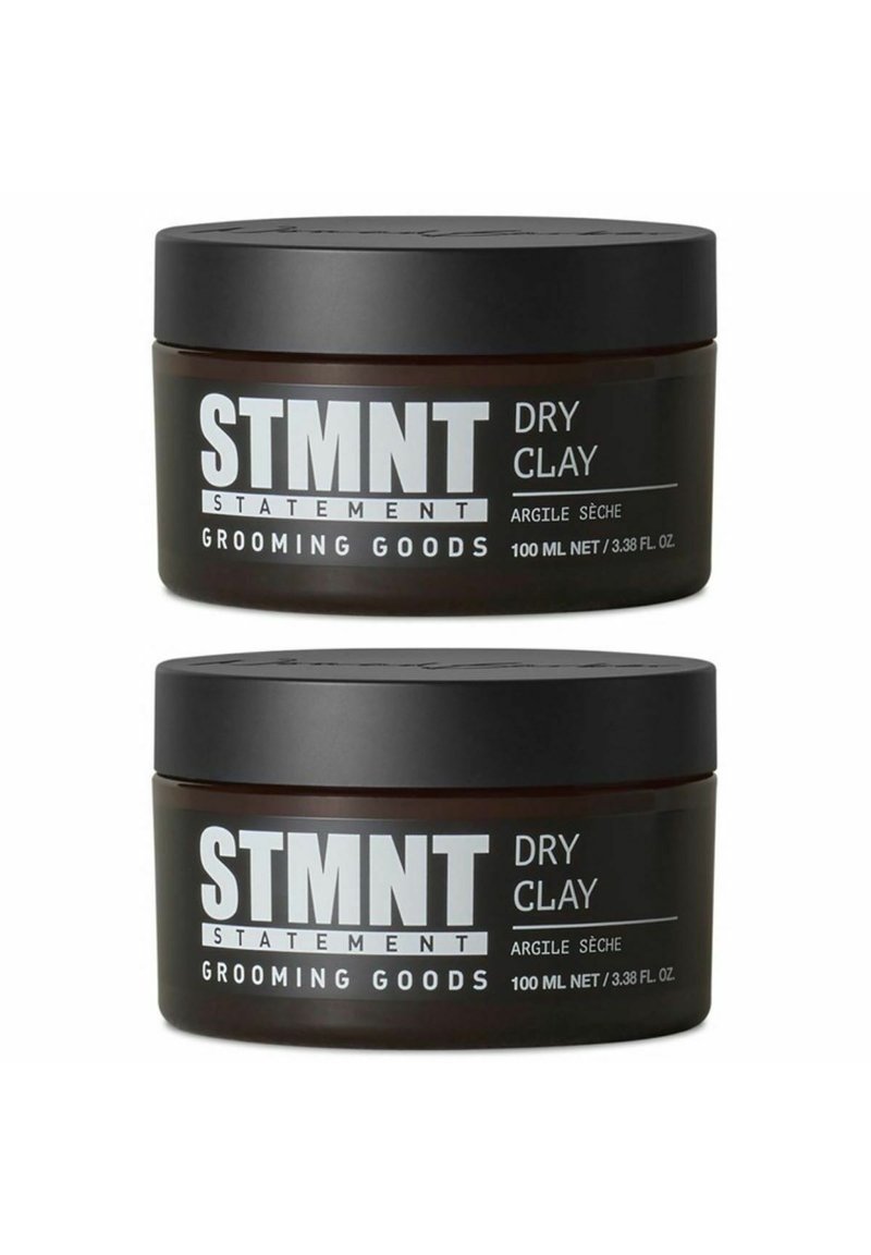 Two dark brown jars of STMT Dry Clay, each 100 ml, with black lids. Labels in bold white text, detailing product name and brand.
