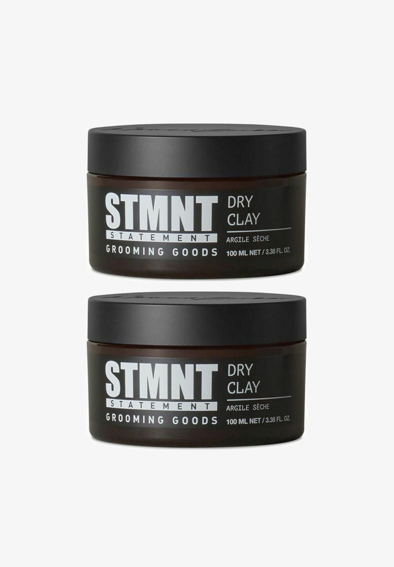 Two dark brown jars of STMT Dry Clay, each 100 ml, with black lids. Labels in bold white text, detailing product name and brand.