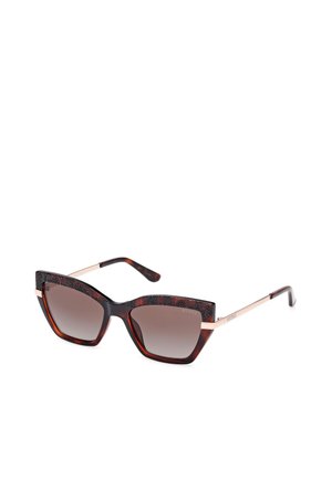 Des lunettes de soleil en forme de yeux de chat avec une monture écaille de tortue et des accents noirs texturés. Les verres dégradés bruns et les bras métalliques complètent le design.