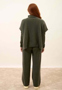 Grön stickad tröja med hög krage och lös passform, parat med matchande vida byxor. Mjuk textur, minimalistisk design.