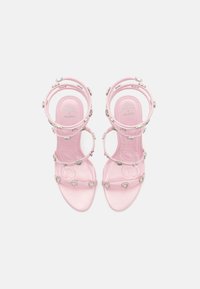 Pink strappy sandals featuring heart-shaped embellishments and silver accents, with a clear, glossy material and minimalist design.