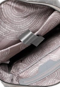 Grijze tas interieur met een gedraaide bedrukte stof met tekst in lichtgrijs. Gladde, licht glanzende ritssluiting en metalen accenten.