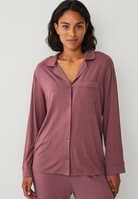 Langarm, knoopsluiting pyjamashirt van zachte, mauve stof. Kenmerkt een klassieke kraag en een enkele borstzak. Glad textuur, relaxte pasvorm.