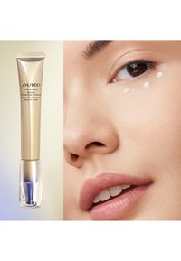 Shiseido Vital Perfection Intensive WrinkleSpot Treatment i ett guldfärgat rör med en klar bas med blå accenter. Vita prickar av produkten på huden.