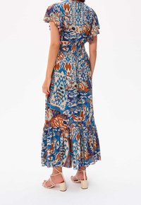 Maksimekko, joka on valmistettu kevyestä kankaasta ja jossa on sininen, ruskea ja kerma beige geometrinen kuvio, frilla-hihat ja kerroksellinen helma.