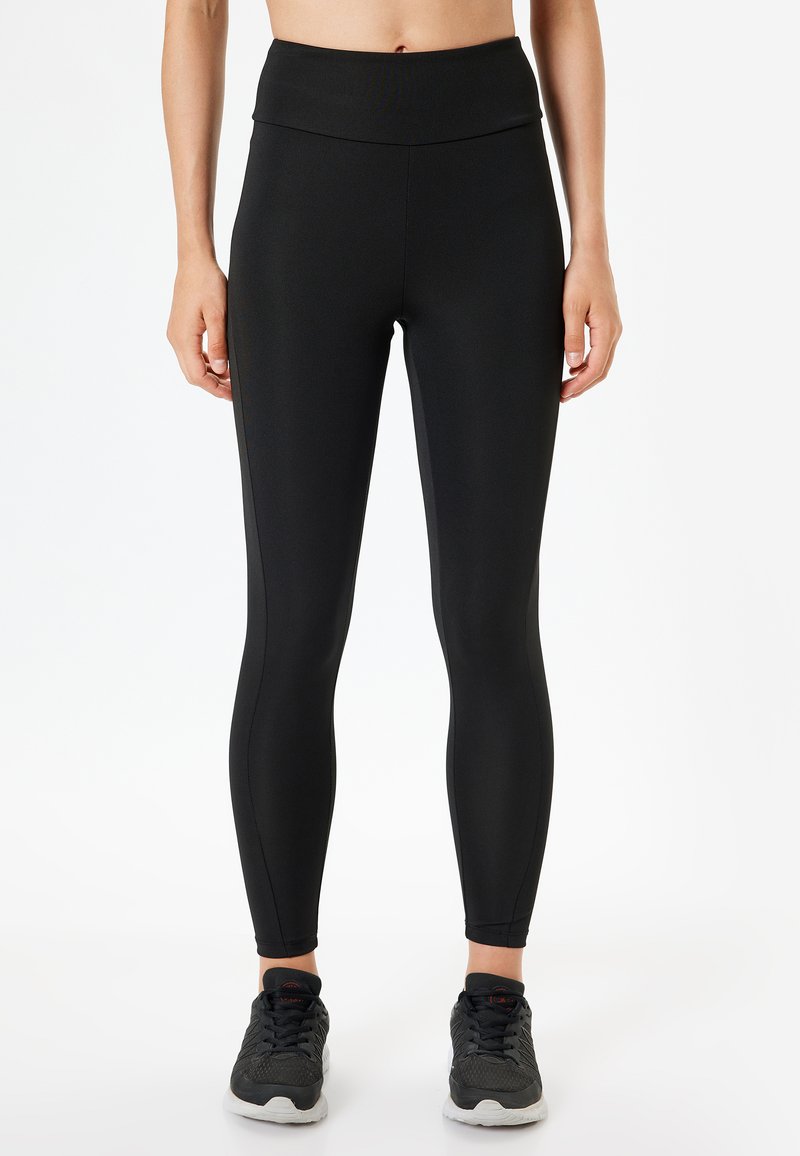 Svarta tights gjorda av elastiskt tyg med hög midja och avsmalnande ben, med en slät yta och minimala sömdetaljer.