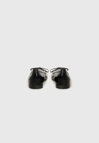 Black leather shoes with a glossy finish, round toes, a low heel, and a lacing detail at the back. Smooth texture and minimalist design.