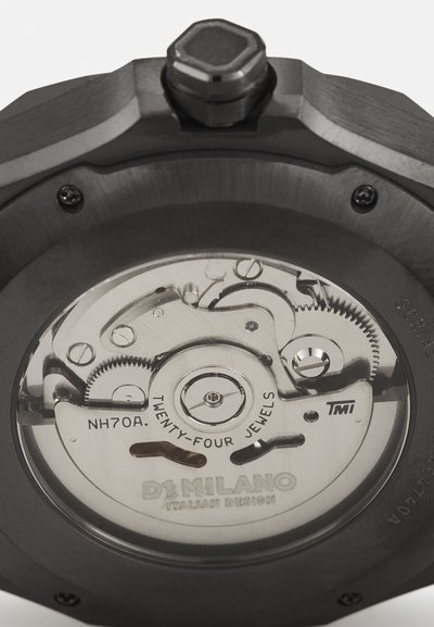 Mechanische Uhr mit transparentem Gehäuseboden, der die komplizierten Zahnräder und ein gebürstetes schwarzes Metallgehäuse zeigt. Die Inschrift umfasst "NH70A" und "D1 MILANO."