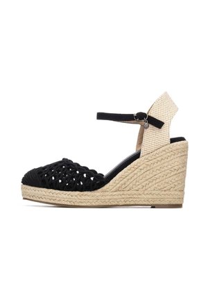 Sandalia de cuña de tela negra tejida con correa en el tobillo y tacón beige tejido. Cuenta con una plataforma de yute texturizada. Diseño de punta redondeada.