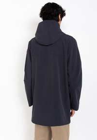 Chaqueta impermeable de un azul marino oscuro, con capucha, mangas largas y un corte holgado. Textura suave con costuras mínimas y un detalle en la espalda.