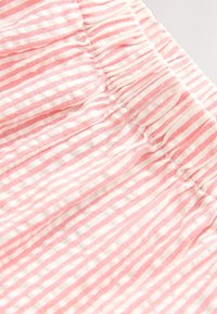 Tessuto a righe rosa chiaro e bianco con finitura strutturata. Presenta dettagli arricciati lungo il bordo, creando pieghe sottili.