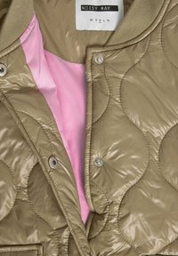 Μπεζ καπιτονέ μπουφάν με κουμπιά τύπου σνάπ, ροζ εσωτερική επένδυση, ριμπ γιακά και ετικέτα "NOISY MAY" που δείχνει μέγεθος μέτριο.