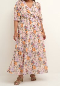 Robe maxi fleurie avec un col en V, des manches courtes et une taille élastique. Présente des fleurs orange, violettes et roses sur un fond clair.