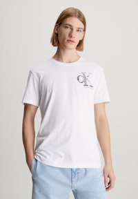 Balta medvilninė t-shirt su apykakle ir trumpomis rankovėmis. Papuošta juodu „CK“ logotipu ir „Calvin Klein Jeans“ tekstu ant krūtinės.