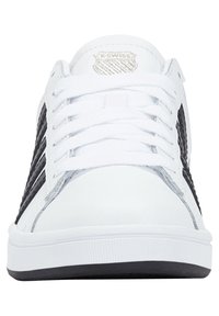 White sneaker featuring a textured black side panel, flat laces, and a silver K-Swiss logo on the tongue. Rubber sole with a textured bottom.