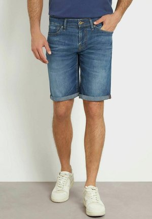 Shorts in denim azzurro chiaro con una finitura sbiadita, orli arrotolati, cinque tasche e chiusura con un solo bottone. Abbinati a sneakers bianche.