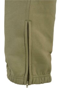 Olive green sweatpants featuring a zippered side pocket, elastic waistband, and ribbed cuffs. Made from a soft cotton blend material.